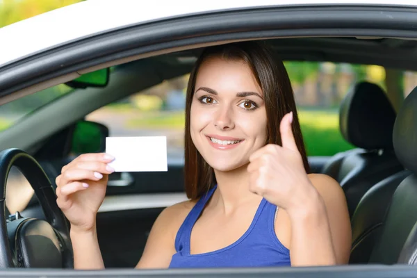 Atractiva mujer dentro del coche mostrando la tarjeta — Foto de Stock