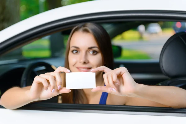 Atractiva mujer dentro del coche mostrando la tarjeta — Foto de Stock