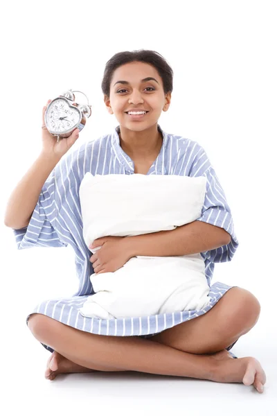 Wanita tersenyum duduk dengan bantal dan jam alarm — Stok Foto