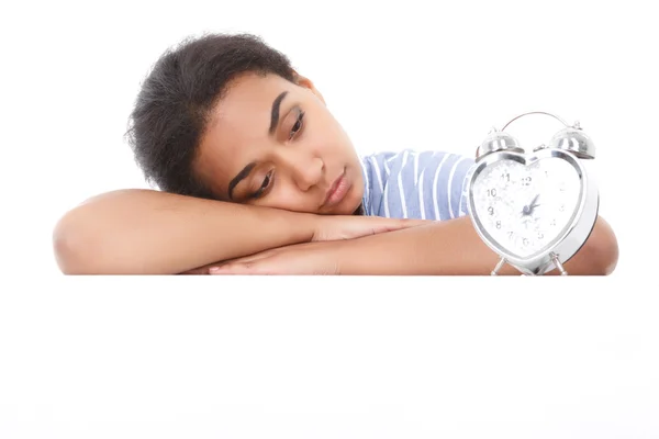 Mulatto girl leaning and looking at alarm clock — Stock Photo, Image