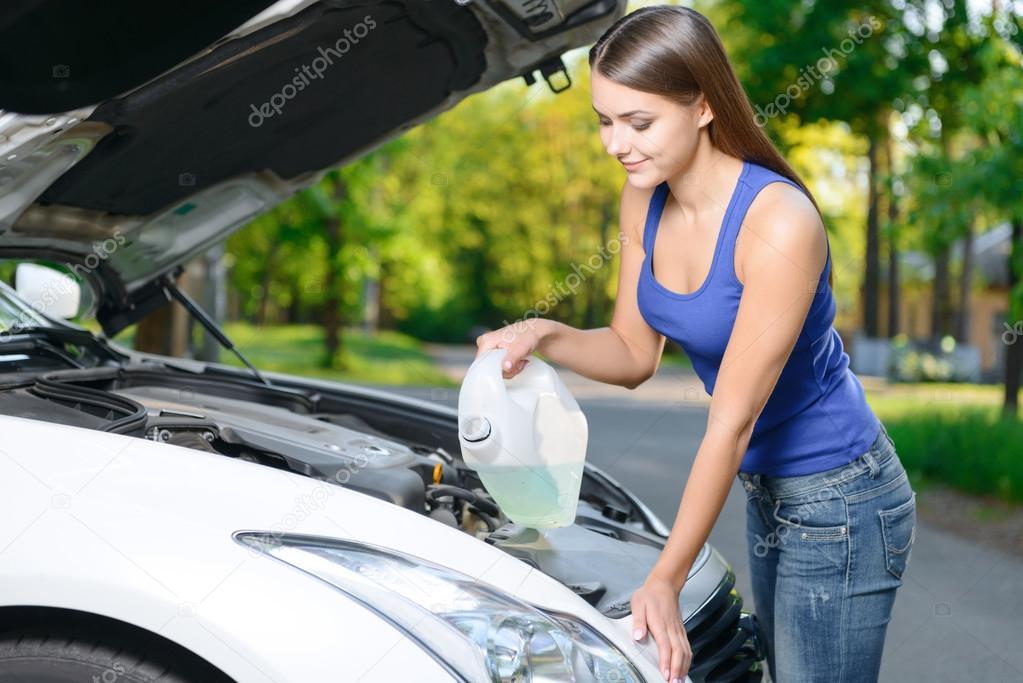 Pretty girl pouring liquid for car