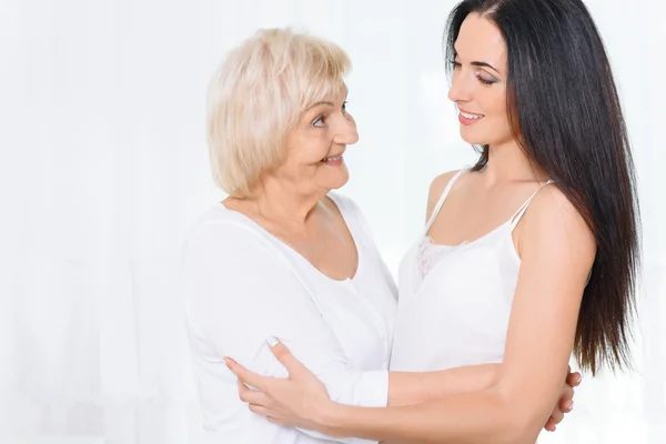 Abuela de pie y abrazando nieta — Foto de Stock