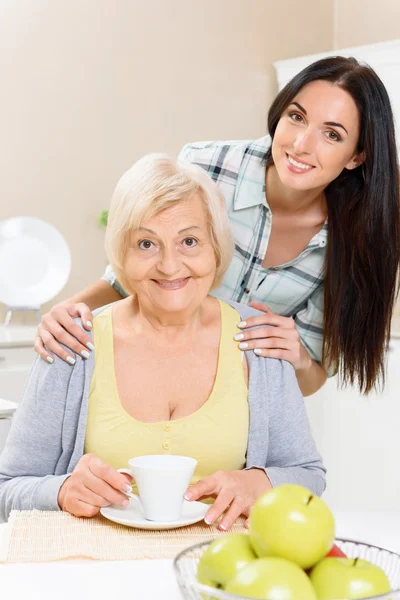 Grandmother and granddaughter sitting in kitchen — Stock Photo, Image