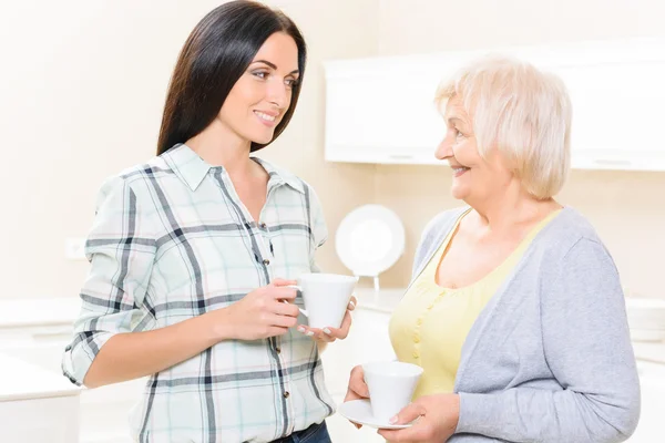 Enkelin und Großmutter stehen mit Tassen — Stockfoto