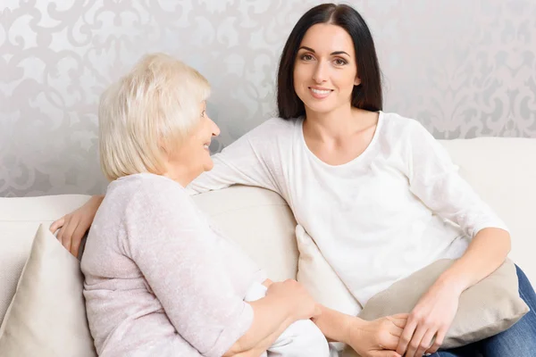 Granny and granddaughter sitting together on couch — Stock Photo, Image