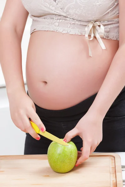 Mujer embarazada cortando manzana — Foto de Stock