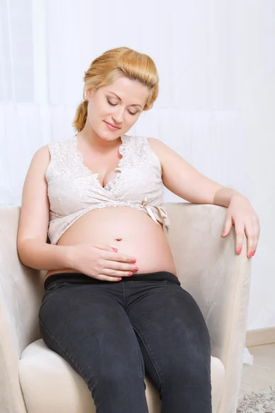 Zwangere vrouw zitten in de leunstoel — Stockfoto