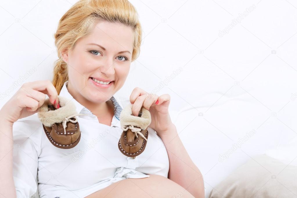 Pregnant mother holding baby shoes