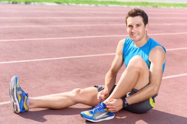 Katta oturan ve spor ayakkabı bağlama adam