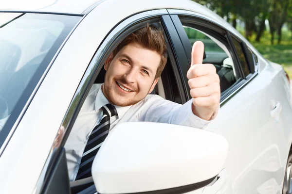 Young man doing thumbs up in car — Stock Photo, Image