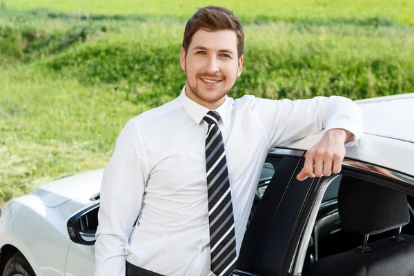 Businessman leaning on roof of car — Stock Photo, Image