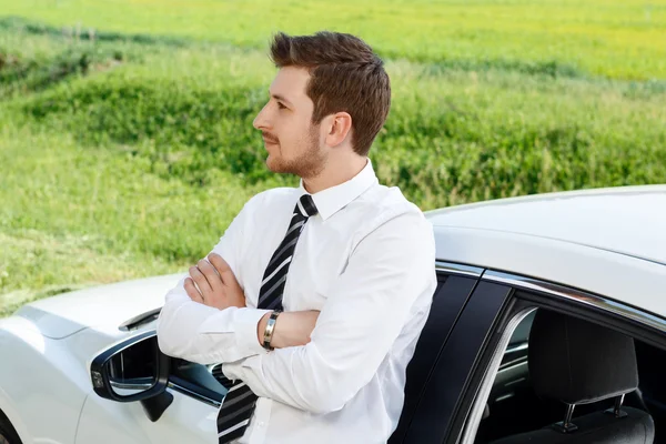 Empresário com as mãos cruzadas perto do carro — Fotografia de Stock