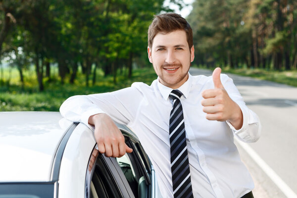 Man with beard thumbing up near car