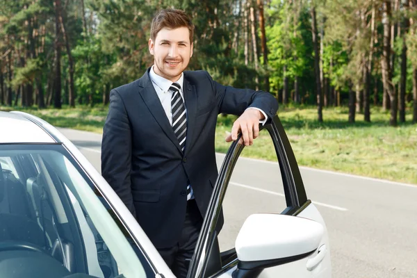 Zakenman die permanent in de buurt van geopende auto — Stockfoto