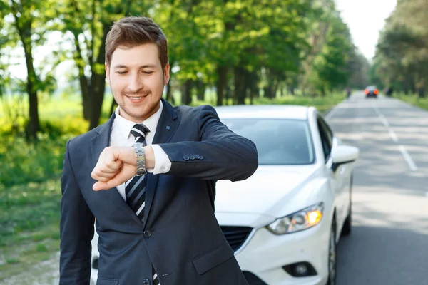 Młody biznesmen sprawdzania czasu w pobliżu samochodu — Zdjęcie stockowe