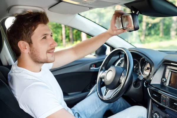 Ung man fastställande spegel i bil — Stockfoto