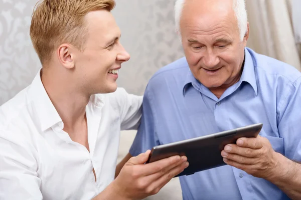 Grandfather and grandson using tablet together