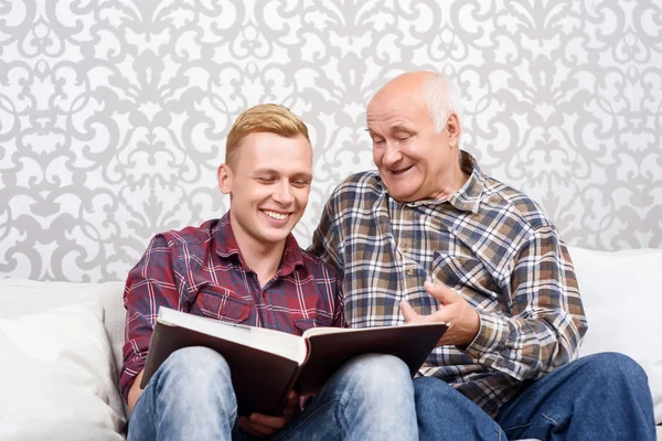 Grandfather and grandson sitting with album — Stock Photo, Image