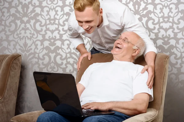 Nieto detrás de su abuelo con portátil —  Fotos de Stock