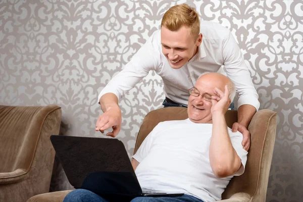 Nipote dietro suo nonno con computer portatile — Foto Stock