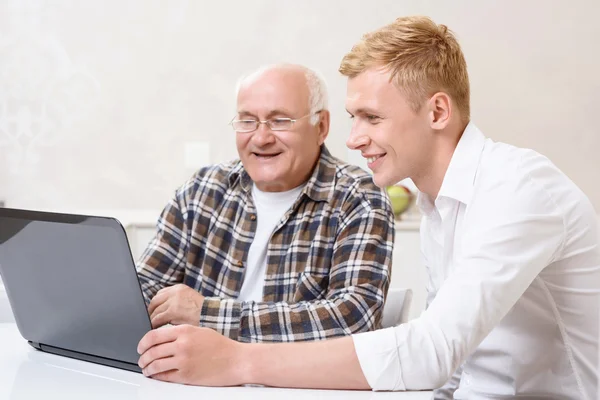 Дедушка и внук сидят с ноутбуком — стоковое фото