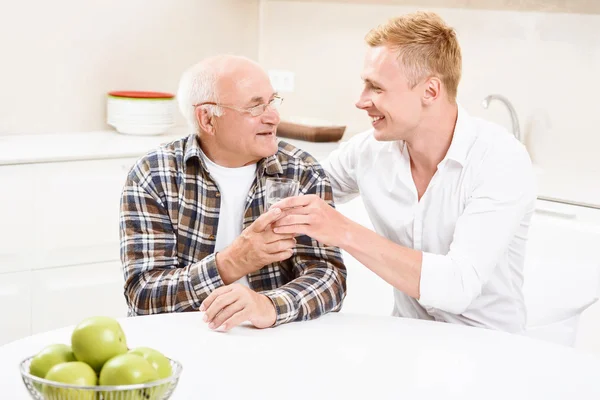 Sonson ger glas med vatten till hans morfar — Stockfoto