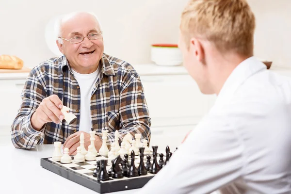 Grandson and grandfather playing chess in kitchen — Stock Photo, Image