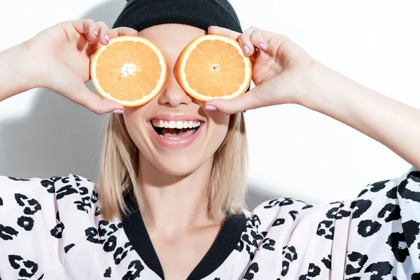 Jong meisje die betrekking hebben op haar ogen met sinaasappelen — Stockfoto