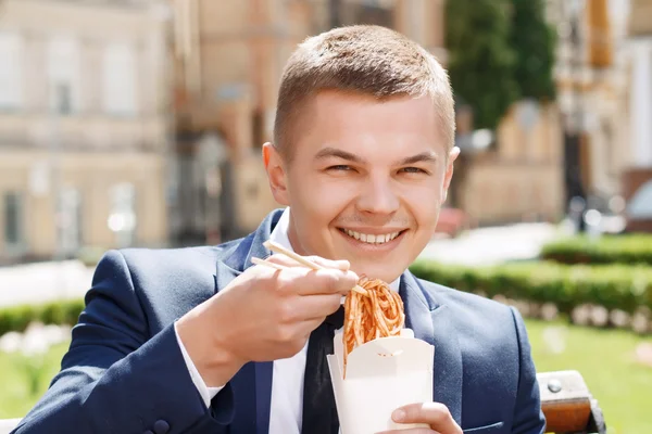 Happy businessman eating Chinese noodles