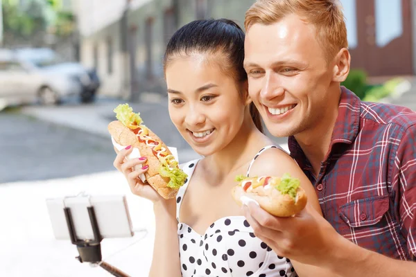 Man och kvinna med korv gör selfie — Stockfoto