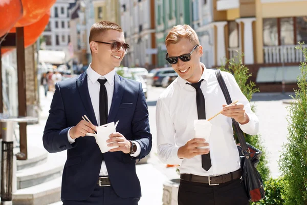Pair of young men walking with street food — Stock Photo, Image