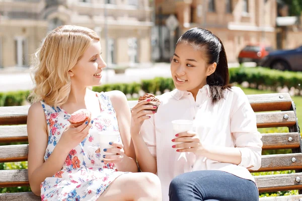 Two girlfriends in park with coffee and cupcakes — Stock Photo, Image