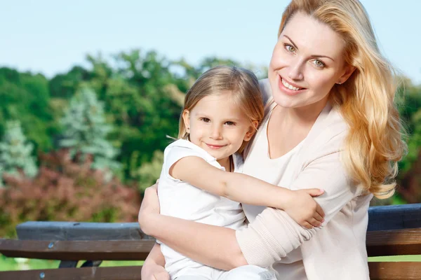 Mother holding her daughter in park