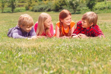 Upbeat children lying on grass in raw 