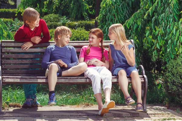 Nice smiling children sitting on the bench — Zdjęcie stockowe
