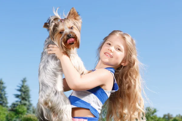 Улыбающаяся маленькая девочка держит собаку — стоковое фото