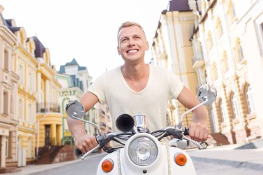 Smiling blond-haired man on scooter 