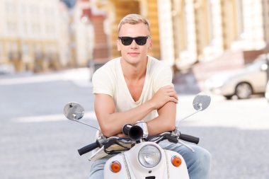 Blond-haired man leaning on scooter 