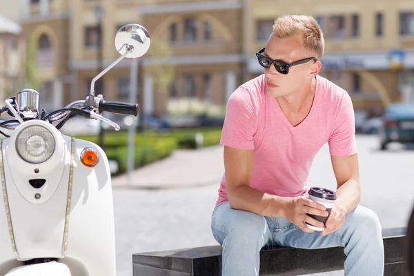 Schöner Mann sitzt mit Kaffee in der Nähe seines Motorrollers — Stockfoto