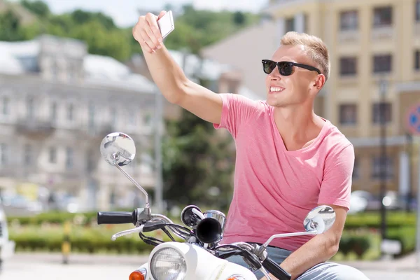 Joven guapo haciendo selfie en scooter — Foto de Stock