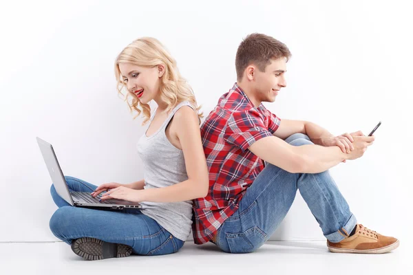 Homem e mulher com telefone celular, laptop — Fotografia de Stock