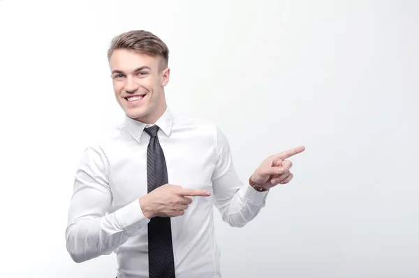 Un hombre de negocios sonriente señalando con los dedos a un lado — Foto de Stock