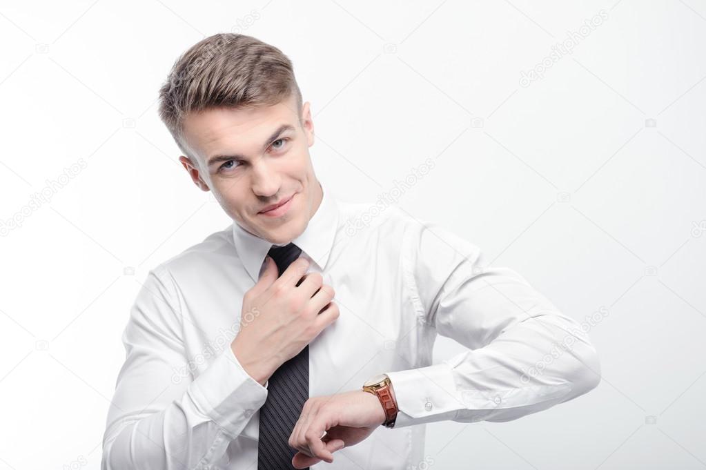 Handsome businessman fixing tie and checking time