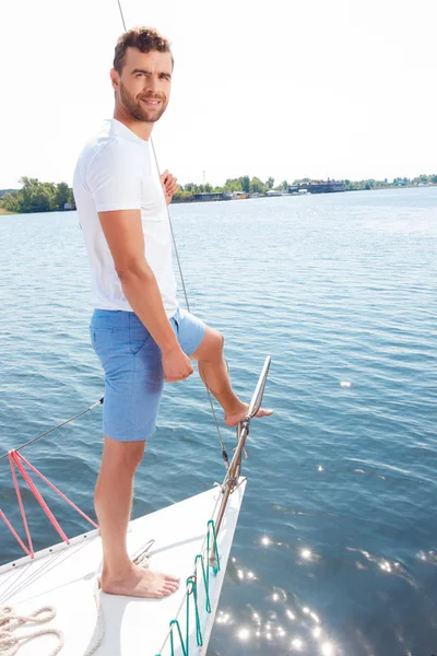 Улыбающийся человек, стоящий на борту яхты — стоковое фото