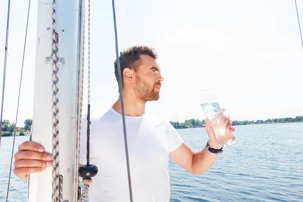 Nice man drinking water on yacht — Stock Photo, Image