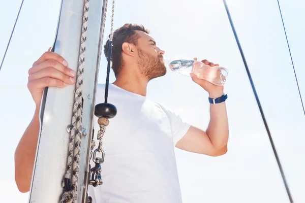 Nice man drinking water on yacht — Stock Photo, Image