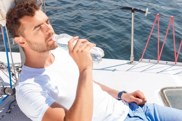 Nice man drinking water on yacht