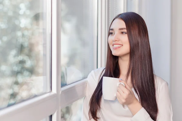 Vrouw die thee drinkt bij het raam — Stockfoto
