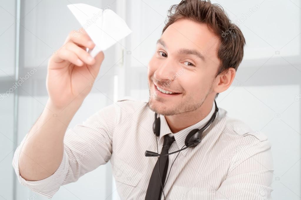 Positive call center operator holding paper plane 