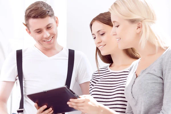Cheerful students holding tablet computer — Stockfoto
